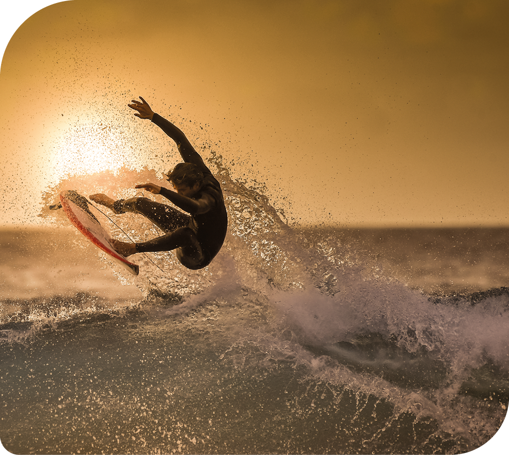 Fotografia de um surfista fazendo uma manobra com sua prancha diante de uma onda, no mar.