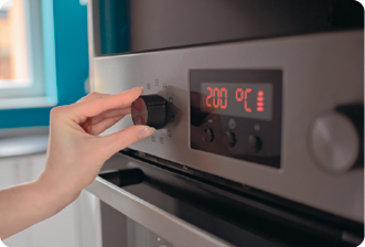 Fotografia de uma mão mudando a temperatura de um forno de cozinha.