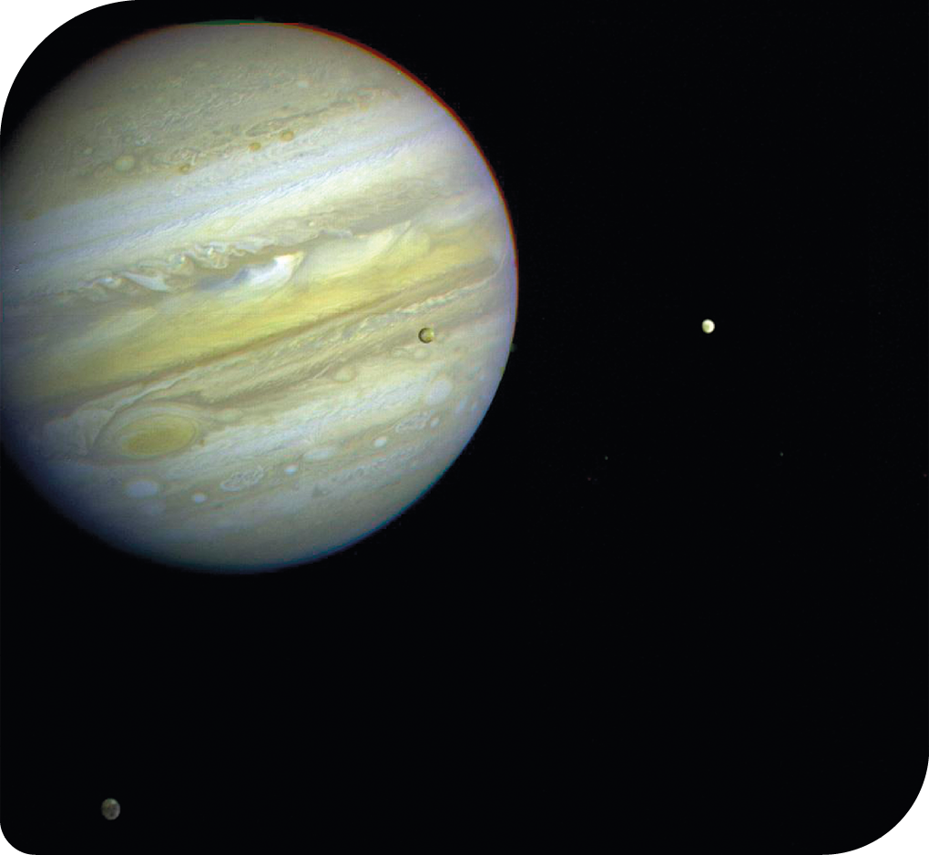 Fotografia do planeta Júpiter, bem próximo, à frente da imagem. Ele tem cores em tons de cinza e marrom claro, que aparecem como faixas na horizontal. Ao lado, bem pequenos, dois satélites naturais e um terceiro, sobreposto a fotografia do planeta Júpiter, à sua frente, chamados de luas de Júpiter.