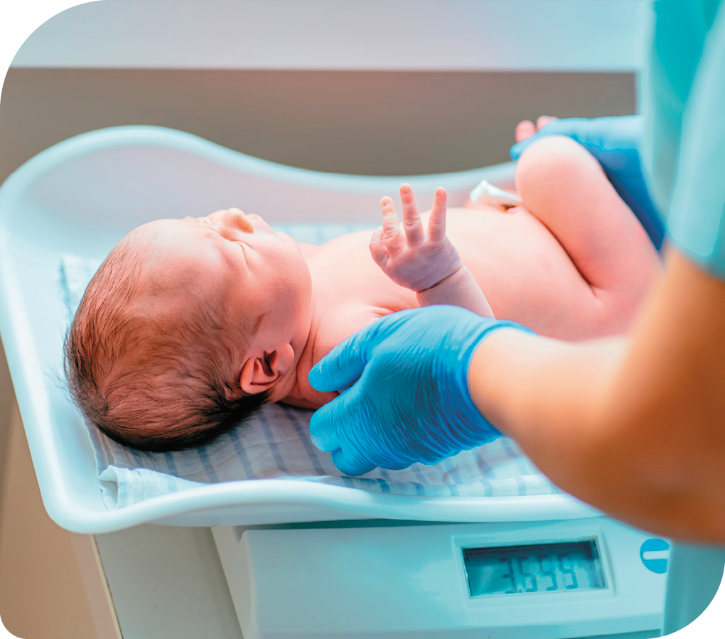 Fotografia de um bebê recém-nascido sendo colocado sobre uma balança. A tela da balança mostra a medida da massa de 3,555 quilogramas.