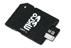 Fotografia de um cartão de memória. O cartão está encaixado na entrada de um adaptador de cartão. No corpo do cartão há o texto 64 G B.
