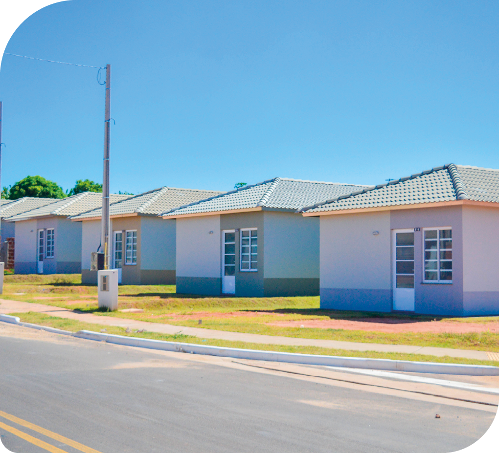 Fotografia de uma rua de um conjunto residencial popular. Além da rua, aparecem várias casas iguais e uma ao lado da outra.