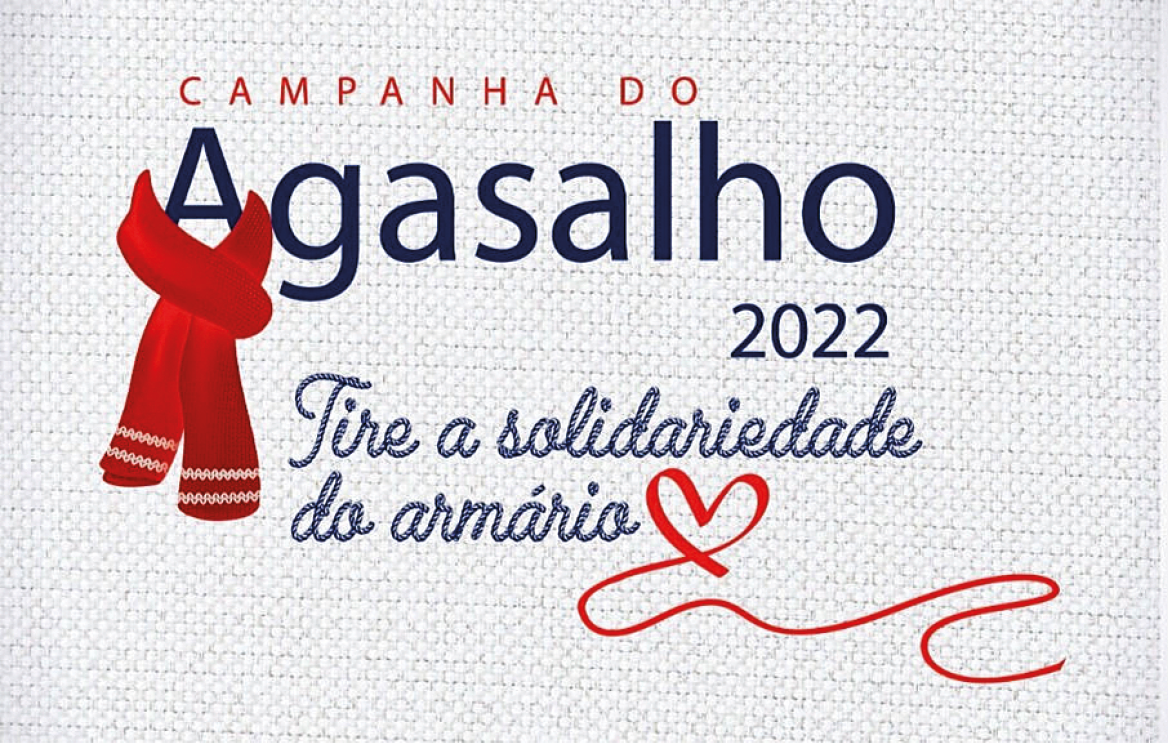 Cartaz na horizontal com fundo em cinza. Texto: CAMPANHA DO AGASALHO 2022. Tire a solidariedade do armário. Na ponta inferior da letra A de agasalho, ilustração de um cachecol vermelho com detalhes em branco, na horizontal. No final do texto, ilustração de um coração vermelho, com uma ponta na horizontal.