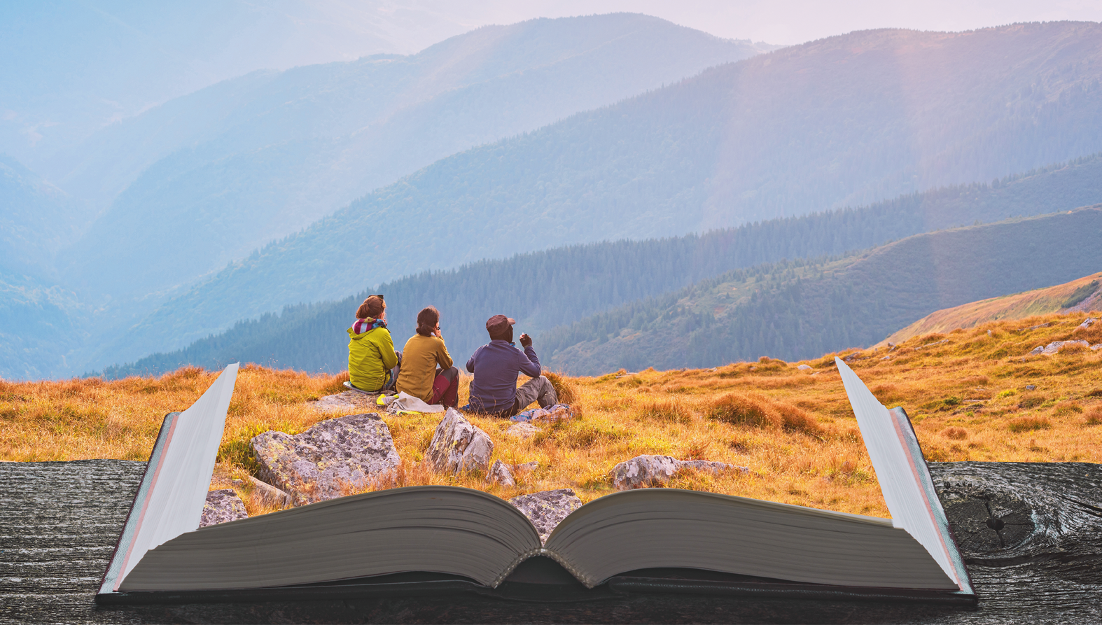 Composição de fotografias. À frente, um livro grande aberto, com páginas que se mesclam à paisagem do local com vegetação seca em amarelo. Sobre o livro, três pessoas sentadas, uma ao lado da outra. Da esquerda para a direita: pessoa de cabelos castanhos, de blusa de mangas compridas em verde. Ao lado, pessoa de cabelos castanhos, de blusa em marrom e na ponta da direita, um homem de chapéu marrom e blusa de mangas compridas em cinza-escuro e calça em bege. Em segundo plano, morros grandes em azul e céu acima, em tons esbranquiçados.