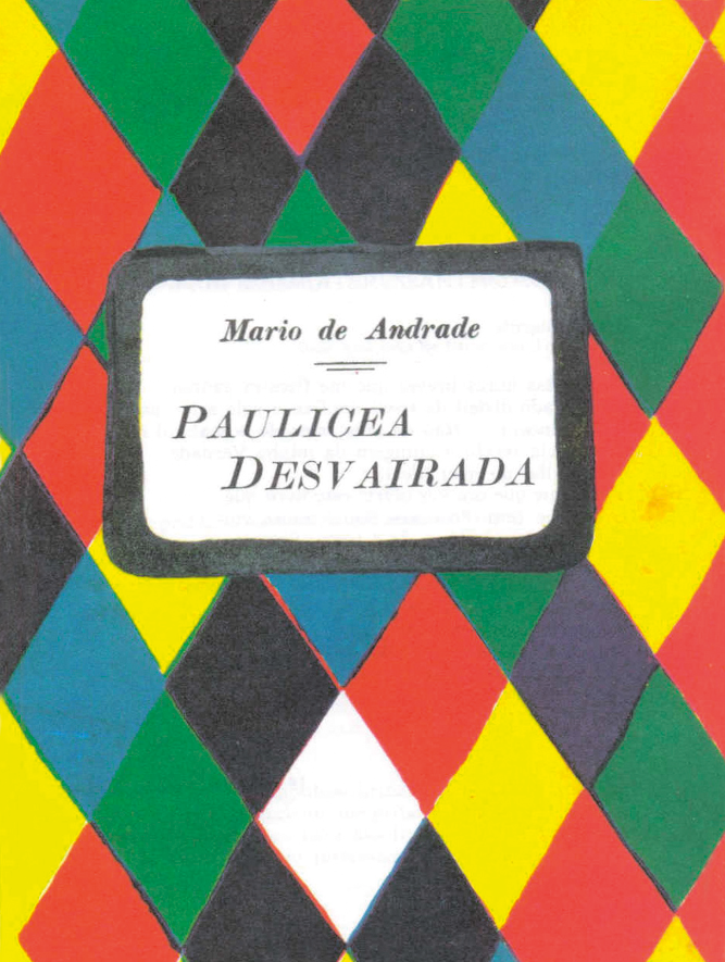 Fotografia. Capa de livro. Fundo com ilustração de losangos um ao lado do outro em vermelho, verde, preto, azul, amarelo e branco. Ao centro, etiqueta branca, com o nome do autor e o título do livro: Mario de Andrade, Paulicea Desvairada.