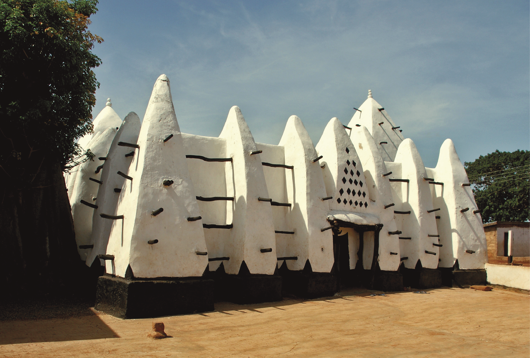 Fotografia. Uma mesquita com paredes brancas e colunas triangulares.