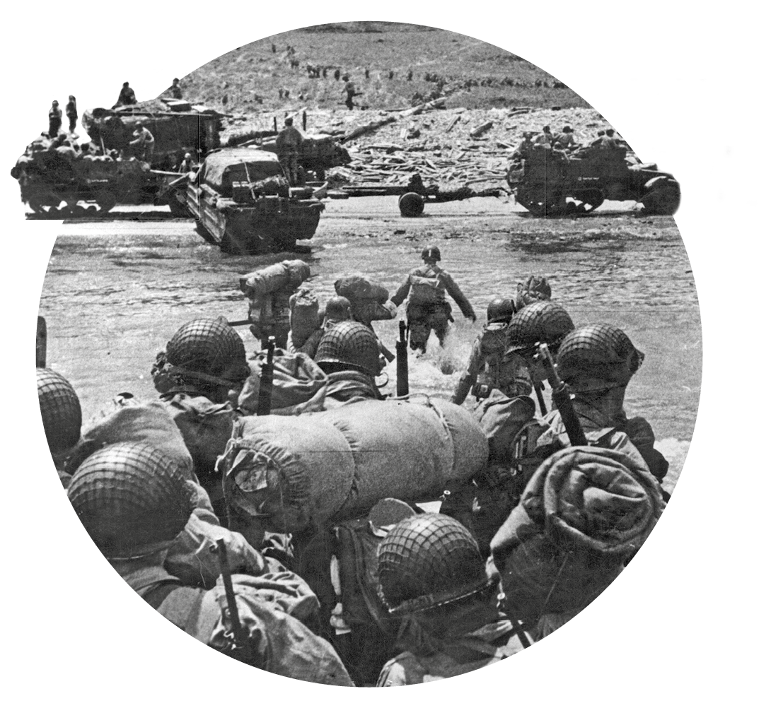 Fotografia em preto e branco. Soldados desembarcando na praia. Alguns estão em pequenos barcos. Na faixa de areia, caminhões e tanques de guerra.