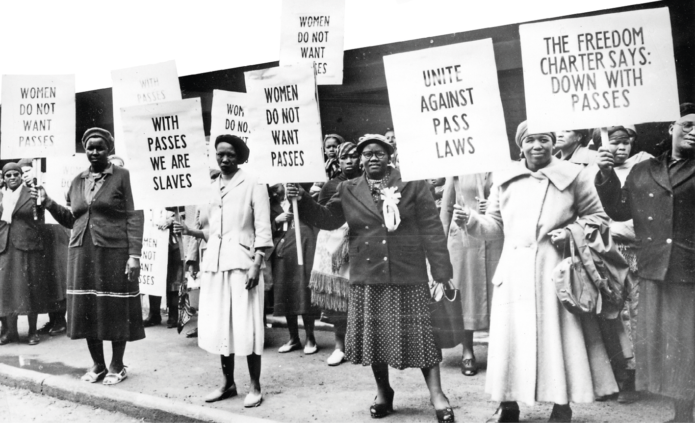 Fotografia em preto e branco. No primeiro plano, mulheres negras em um protesto. Carregam diversos cartazes com dizeres e palavras de ordem.